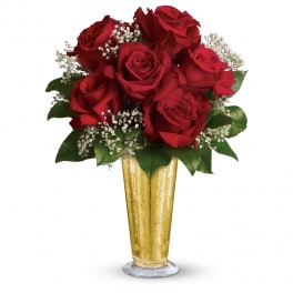 Arrangement of red roses with white filler flowers in a tall gold vase
