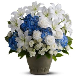 White lilies and roses with blue hydrangeas arranged in a gray pot