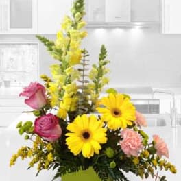 Yellow and pink floral arrangement in a green container
