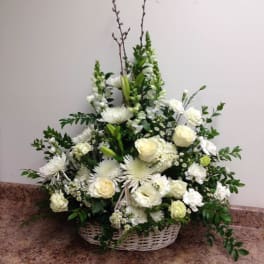White floral arrangement in a wicker basket with roses and lilies
