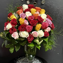 Mixed roses in a glass vase with glossy greenery