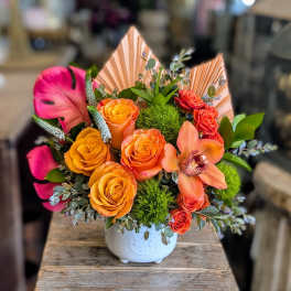 Bright bouquet of orange and pink roses in a white vase