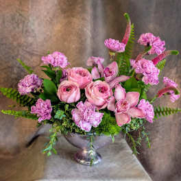 Pink roses and orchids arranged in a silver pedestal vase