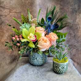 Peach roses and green orchids in an owl planter with peacock feathers