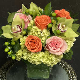 Mixed bouquet of roses, orchids, and hydrangeas in a glass vase