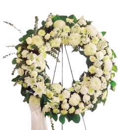 White floral wreath on an easel with a ribbon drape