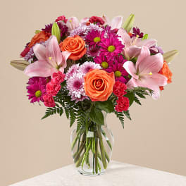 Pink lilies and orange roses in a clear glass vase