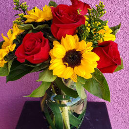 Bouquet of red roses and yellow sunflowers in a glass vase