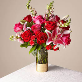 Bouquet of red and pink roses with lilies in a glass vase
