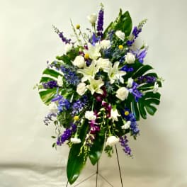 Standing floral spray with white lilies, roses, and purple flowers
