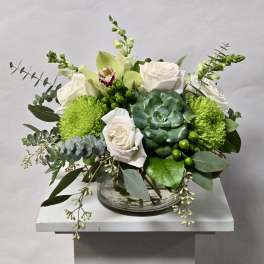 White roses and green blooms arranged in a clear glass bowl.