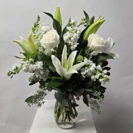 White roses and lilies arranged in a clear glass vase