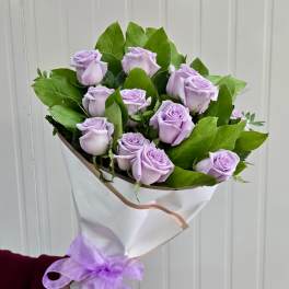 Bouquet of lavender roses wrapped in white paper with a purple ribbon