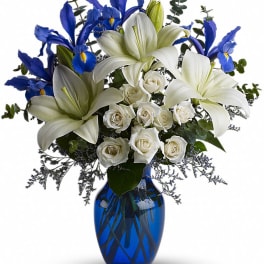 White lilies and roses with blue irises in a cobalt vase