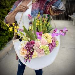 Woman holding a large pastel bouquet in a white tote-style container