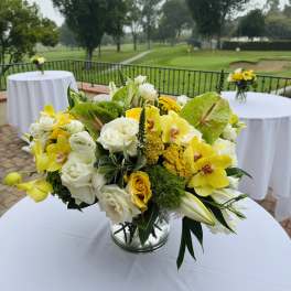 Yellow and white floral centerpiece in a glass vase