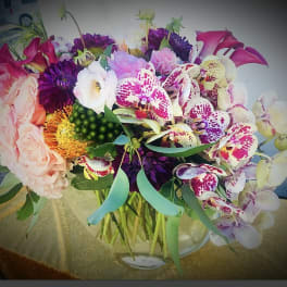 Mixed bouquet with orchids, roses, and calla lilies in a glass vase