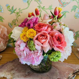 Colorful bouquet of roses, hydrangeas, and tulips in a glass vase