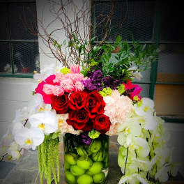 Large floral arrangement with red roses and white orchids in a glass vase