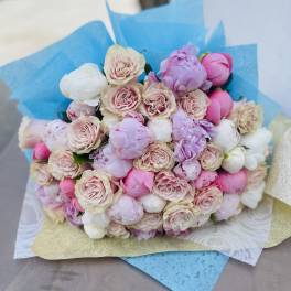 Bouquet of pink and white roses and peonies wrapped in blue paper