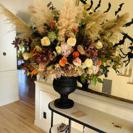 Large autumn floral arrangement in a black urn with pampas grass and mixed blooms