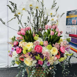 Large floral arrangement with white orchids, pink tulips, and mixed roses in a decorative vase