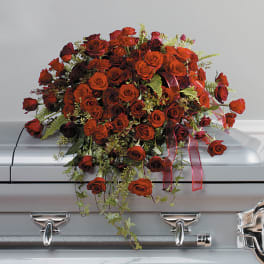 Red rose casket spray with cascading blooms on a silver casket
