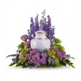 White cremation urn surrounded by lavender and purple flowers with taller blooms at the back.