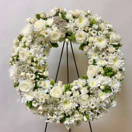 White floral wreath on a black stand