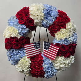 Red, white, and blue floral wreath with two small American flags