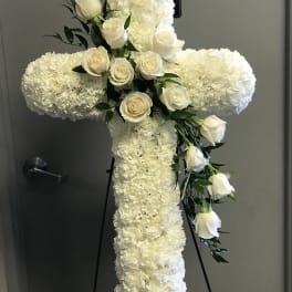 White floral cross on a stand with white roses