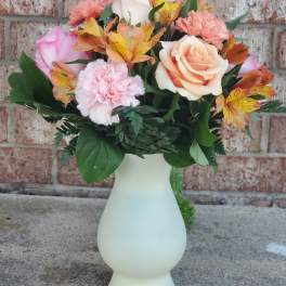Bouquet of peach and pink roses with carnations in a white vase