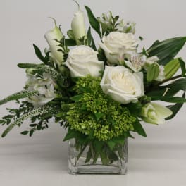 White roses and calla lilies in a clear glass vase
