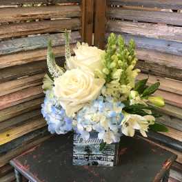 White roses and blue hydrangeas in a decorative square container