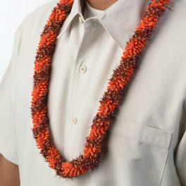 Orange and red floral lei worn around the neck over a light beige shirt