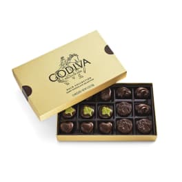 Open gold box of assorted dark chocolates with the lid propped behind it.