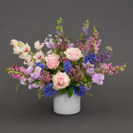 Pink roses and purple flowers arranged in a white vase
