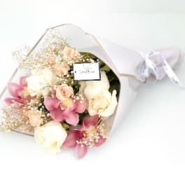 Bouquet of pink and white flowers wrapped in clear paper with a ribbon