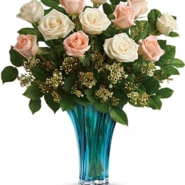 Pink and white roses arranged in a blue glass vase