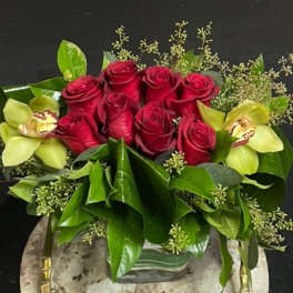 Red roses with pale green orchids in a low vase arrangement