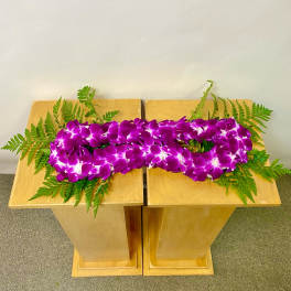 Purple orchid arrangement with fern accents on two wooden pedestals