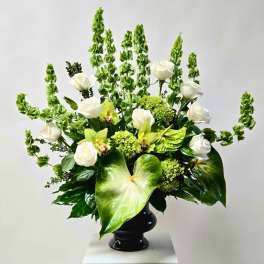 White roses and green orchids in a black vase