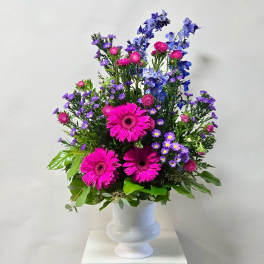Pink and purple mixed flowers arranged in a white vase