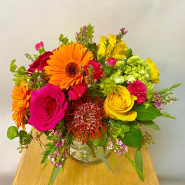 Bright mixed bouquet in a clear glass vase with roses and gerbera daisies