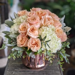 Peach roses and white hydrangeas in a copper vase