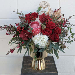 Red roses and white hydrangea in a gold vase with eucalyptus