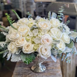 White rose arrangement in a silver vase with pale foliage
