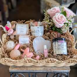 Gift basket with pink roses and bath items in a woven tray