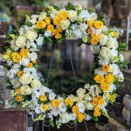 Large floral wreath with yellow and white roses and white daisy-like flowers