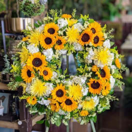 Circular wreath of sunflowers and white flowers on an easel